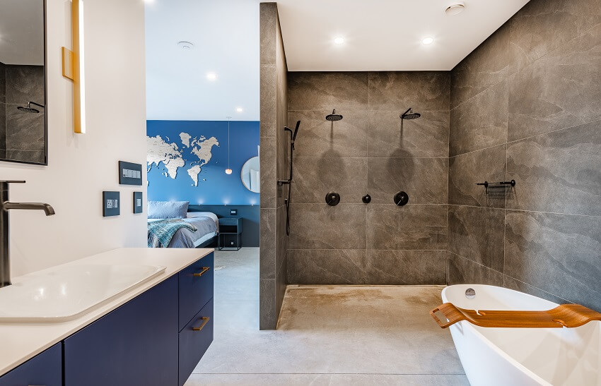 large open concept bathroom with tub and double shower and blue cabinets